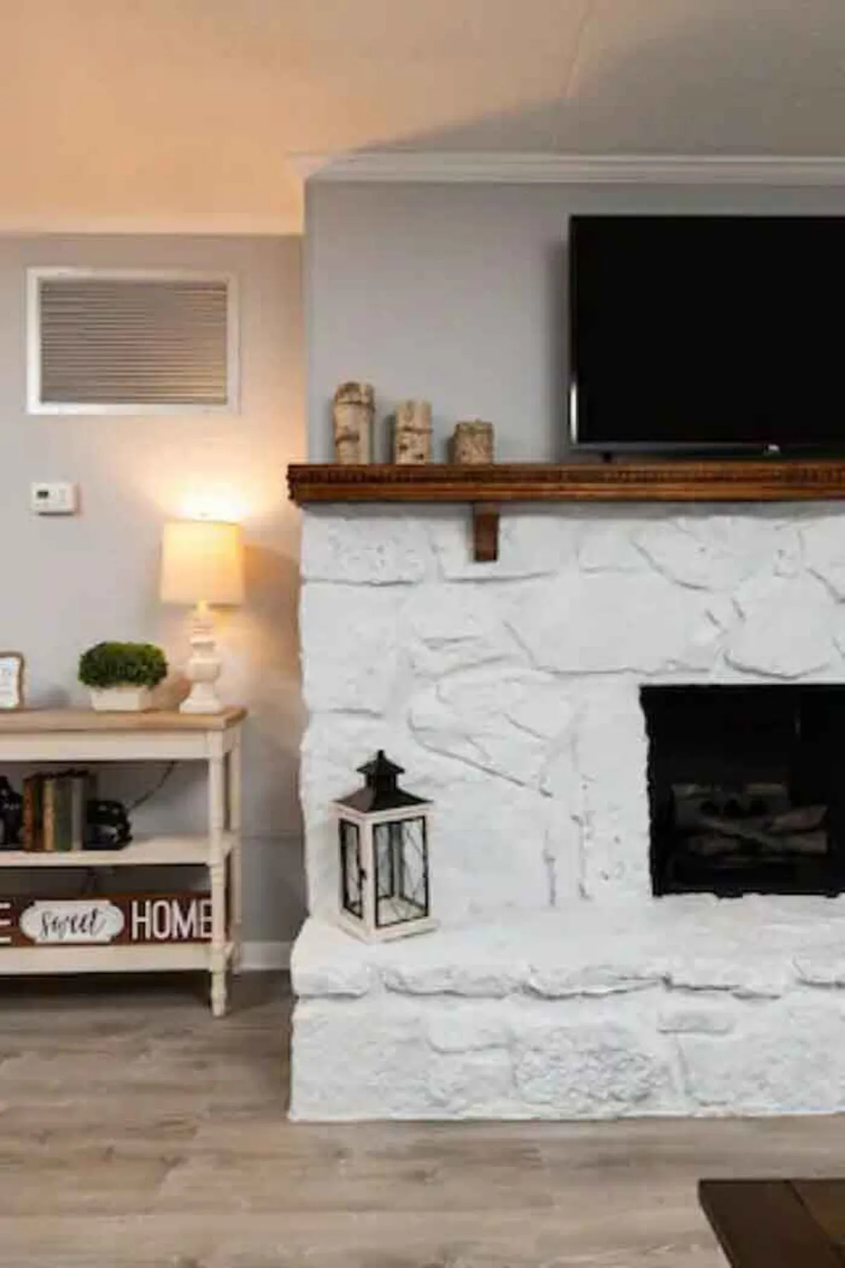 A modern, tastefully decorated living room features a glowing fireplace, a cozy seating area, ambient lighting, and a TV on the mantel—creating an inviting spot for relaxation and intimate evenings.