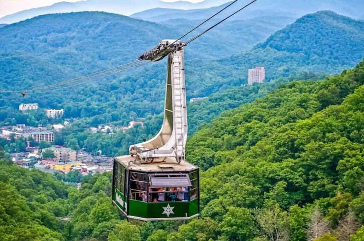 A sweeping vista of a gondola gliding above a mountain range, with the charming town of Gatlinburg nestled below. The image offers a sense of adventure and togetherness, ideal for sightseeing and capturing memorable moments as a group.